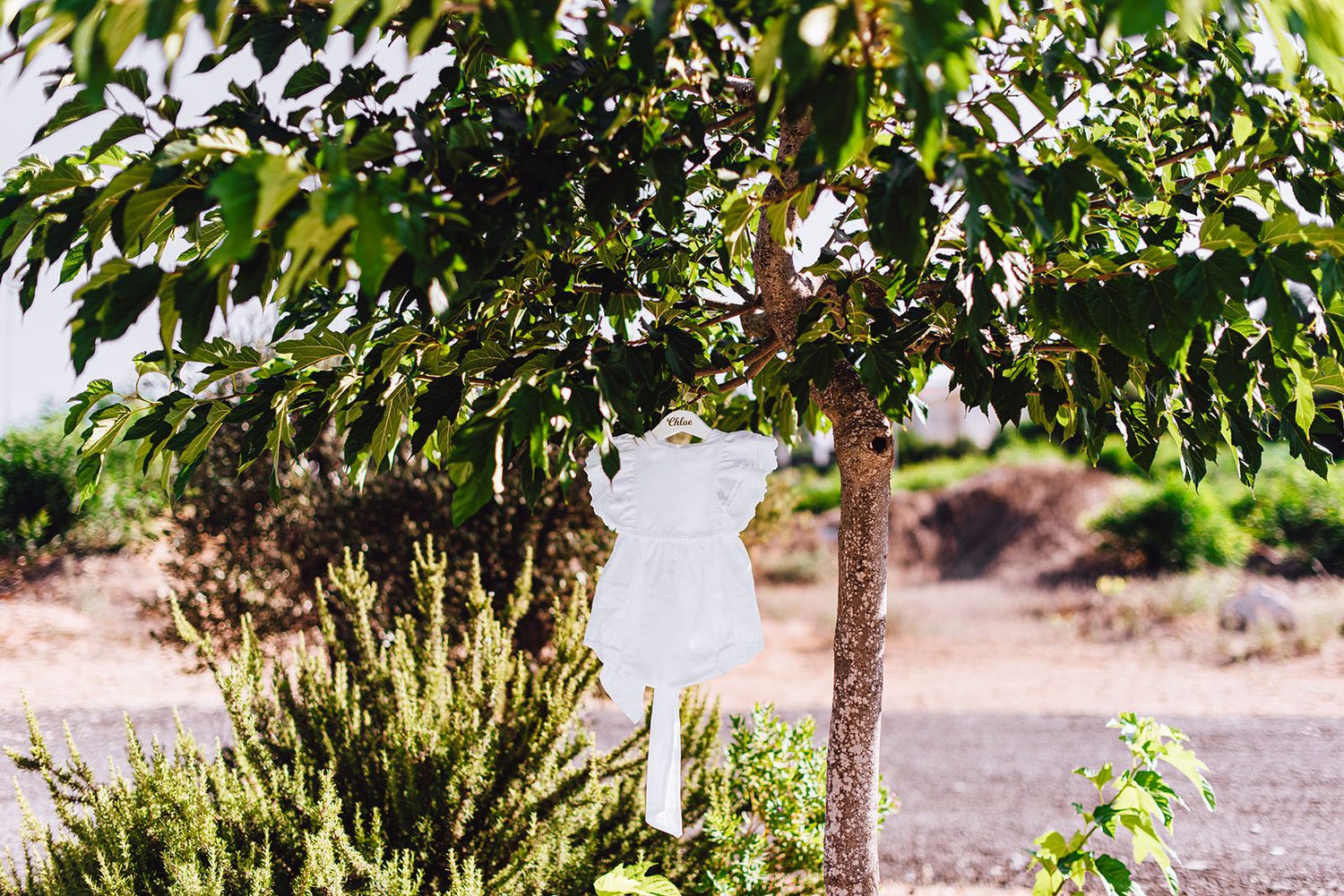 Baby girl’s white christening dress hanging from a tree before the christening in Protaras