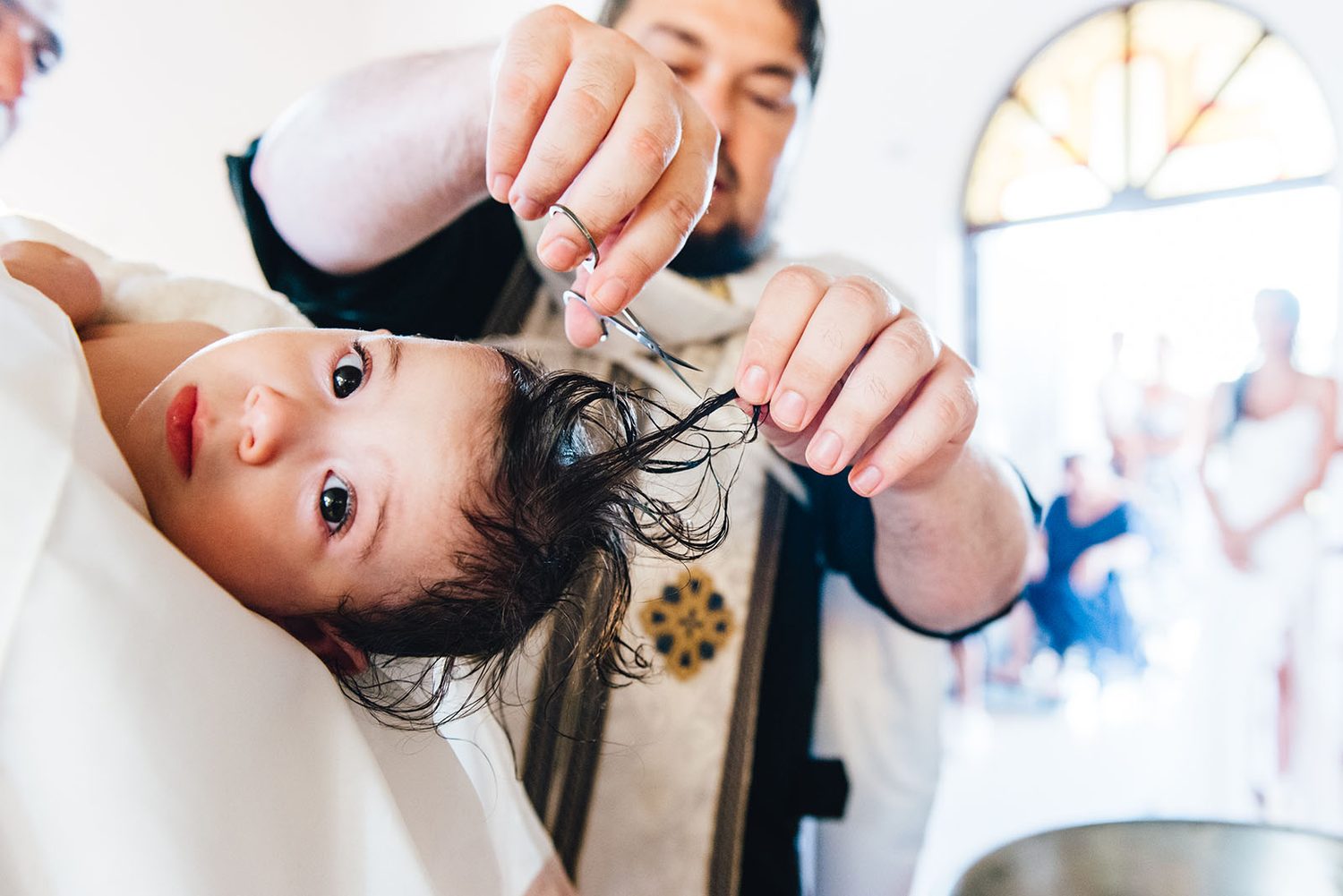 Priest cutting a lock of baby Chloe’s hair during her christening in Protaras