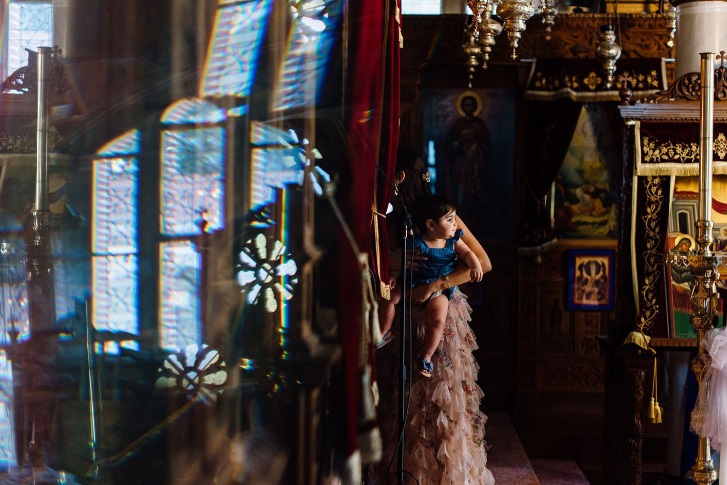 girl in a blue top and ruffled pink skirt looking out from a church doorway