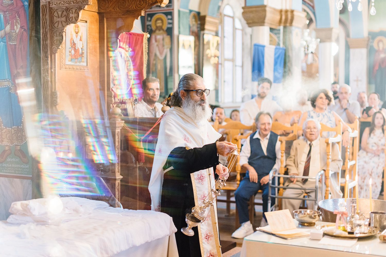 Priest holding a censer during the christening while guests watch from the pews